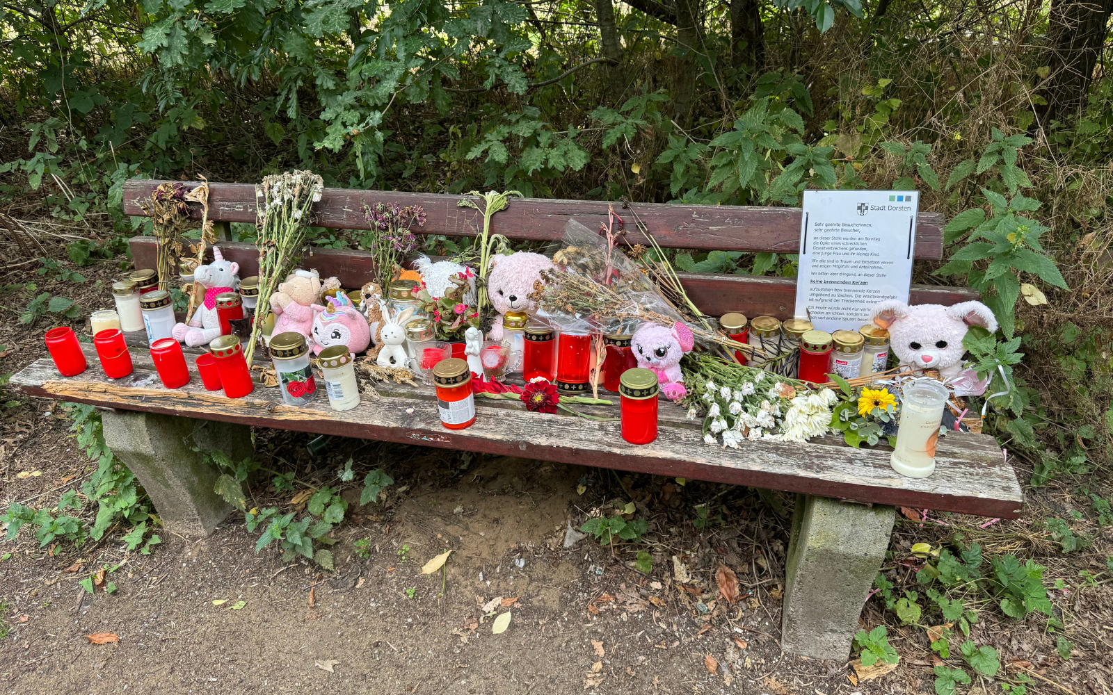 Auf einer Bank am Tatort in Dorsten sind unzählige Kerzen und Kuscheltiere aufgestellt worden. 