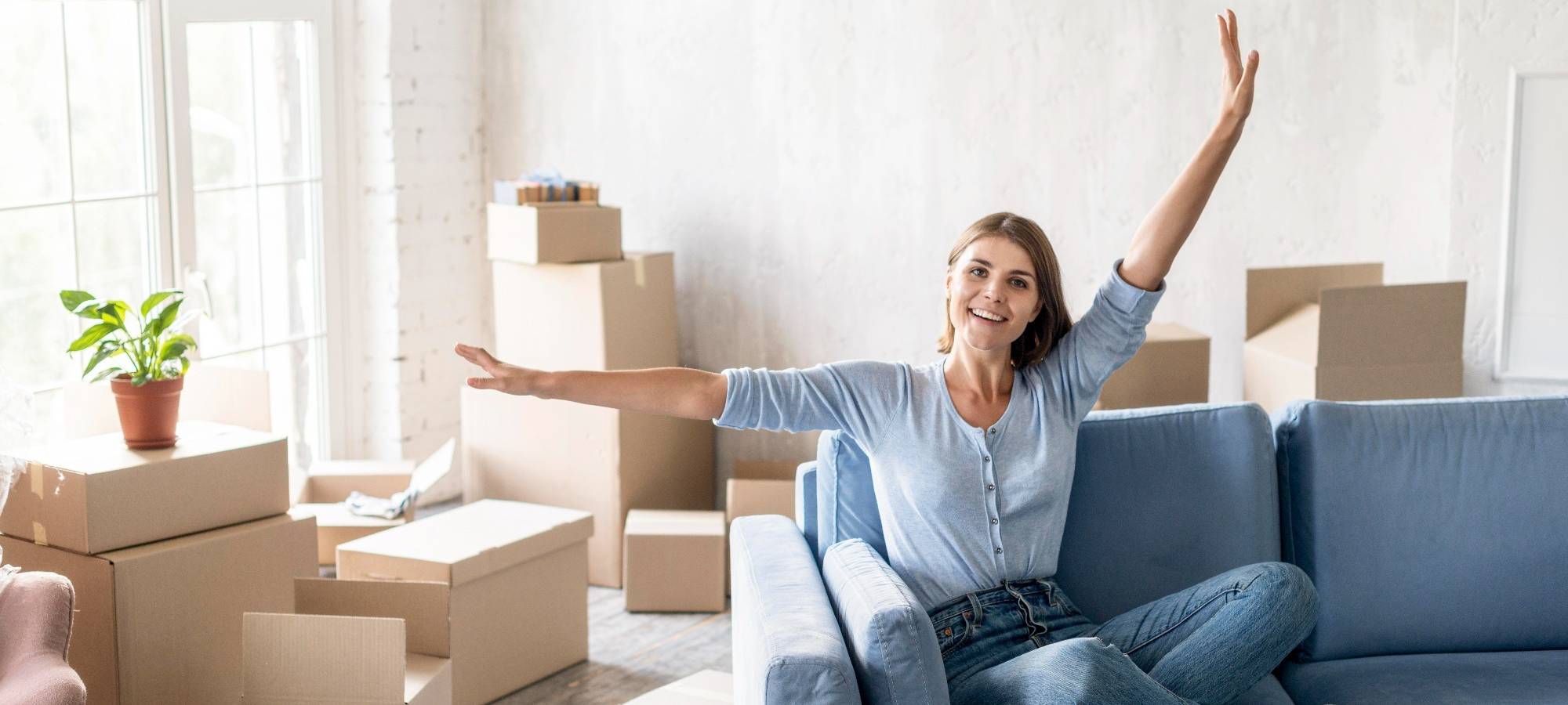 Eine Frau sitzt auf einer Couch in einer frisch bezogenen Wohnung, die noch nicht fertig eingerichtet ist. (Symbolbild)