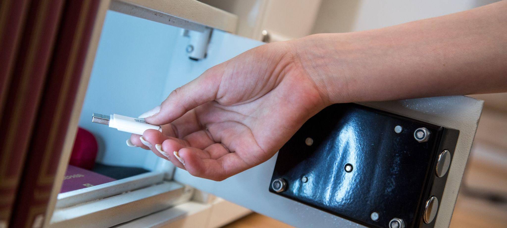 Eine Frau legt einen USB-Stick in einen Safe