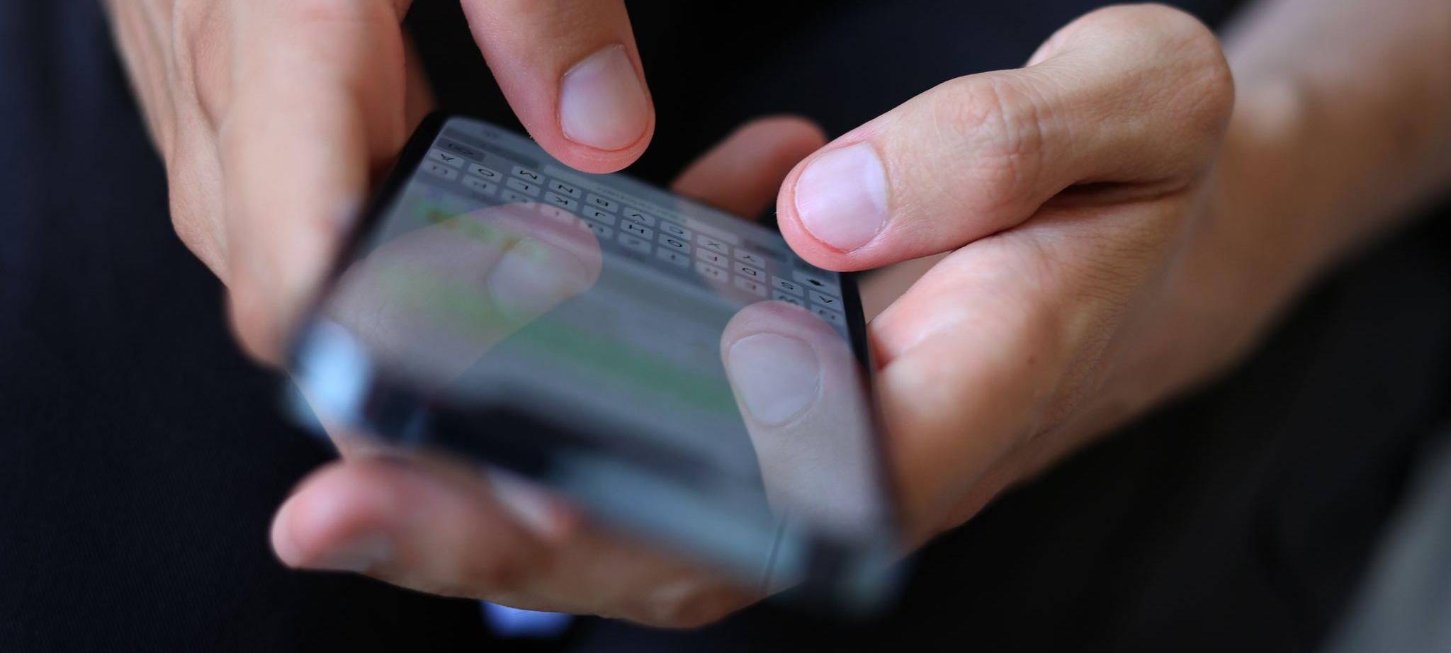 Mann tippt auf einem Smartphone eine WhatsApp Nachricht