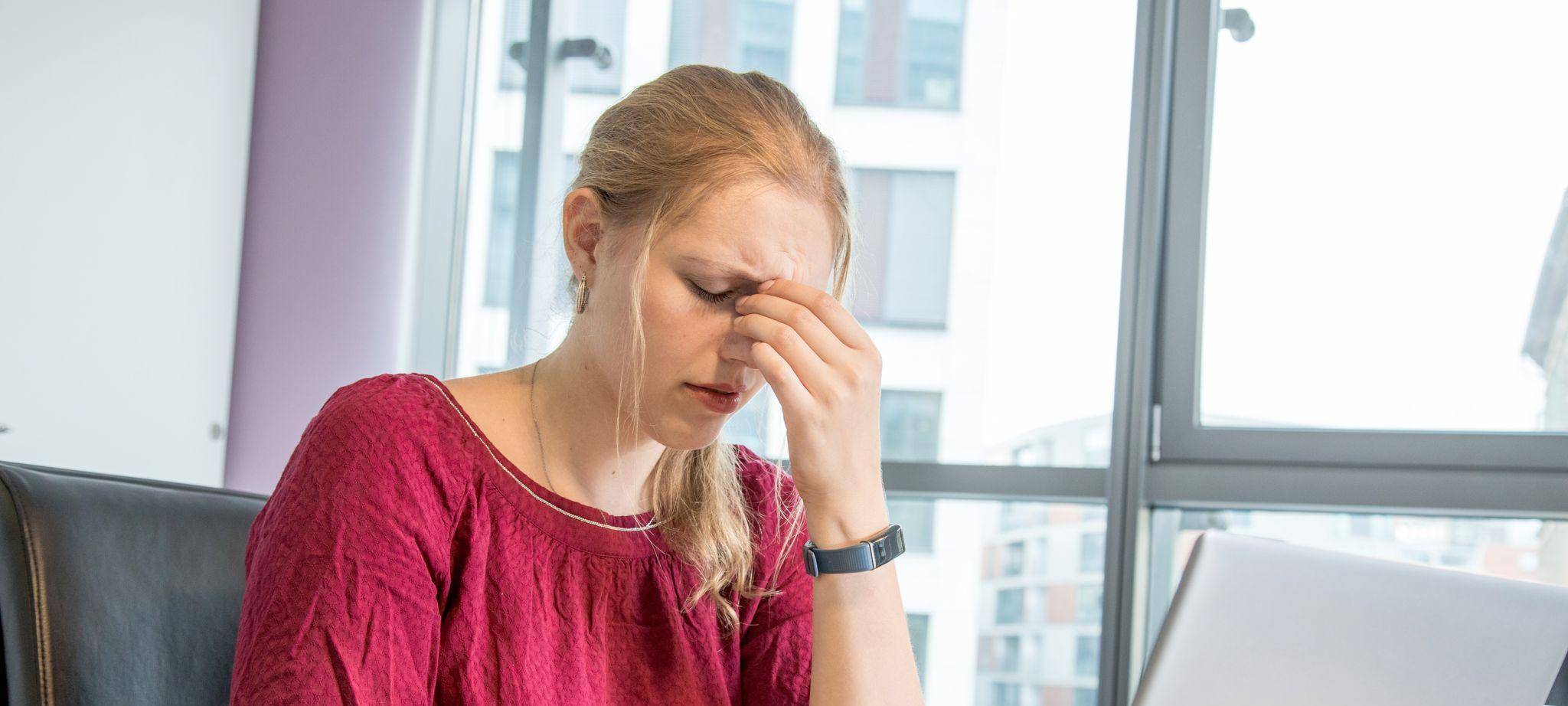 Eine Frau reibt sich die Augen am Arbeitsplatz