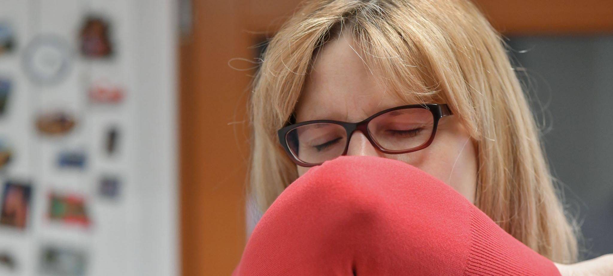 Eine Frau hustet in ihre Armbeuge