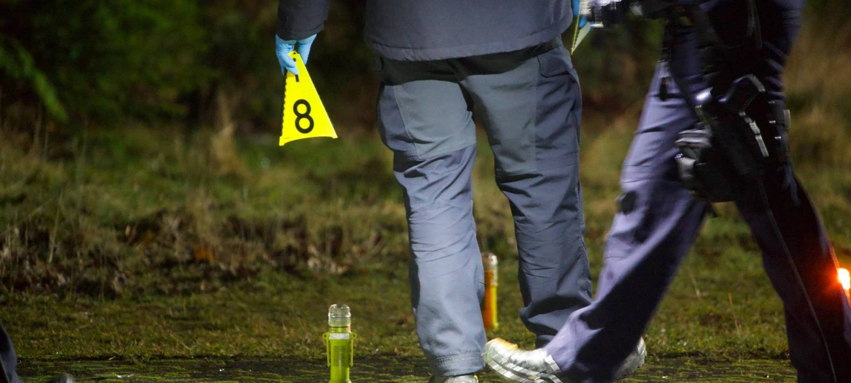 Polizisten sichern mit gelben Markierungen Spuren auf einer Wiese