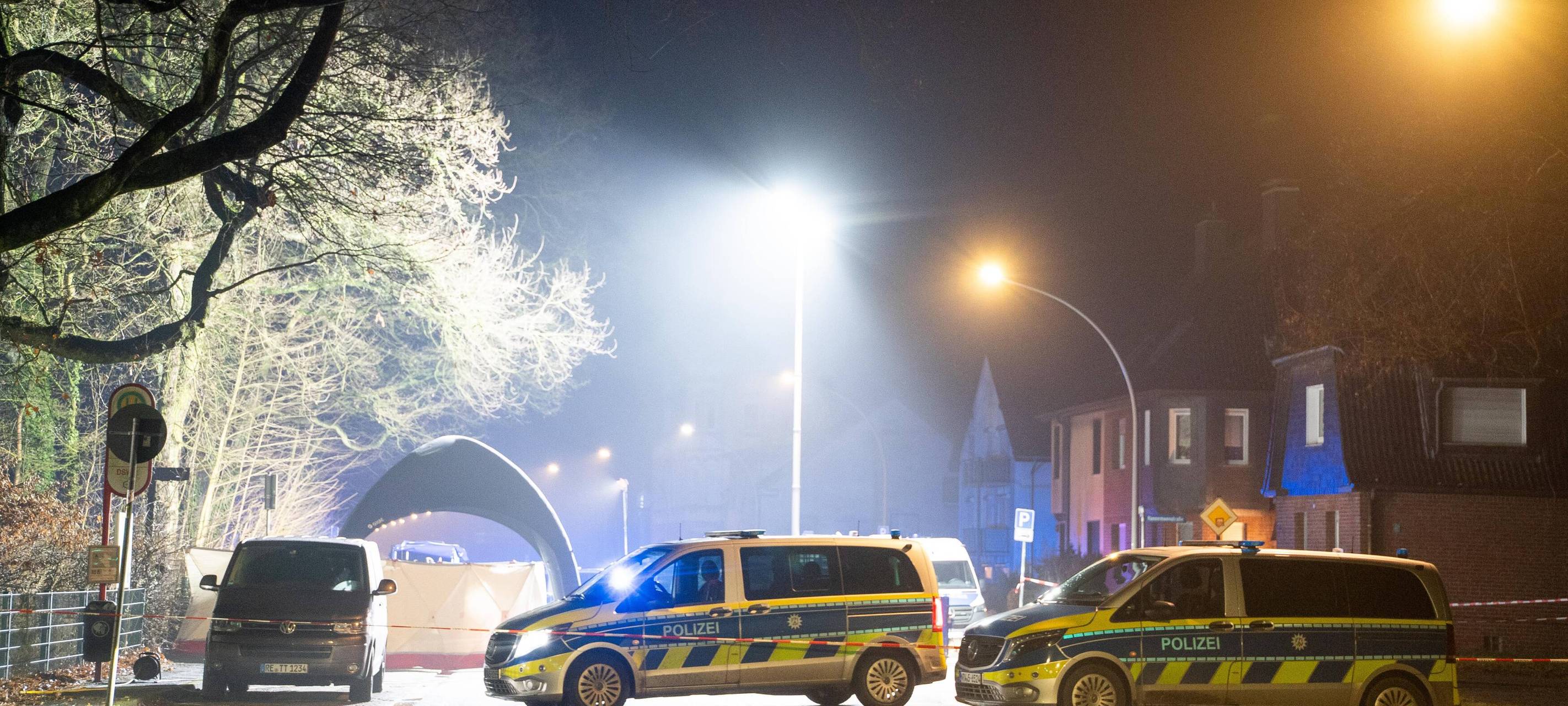 Polizeiautos stehen vor einer ausgeleuchteten Straße am Tatort