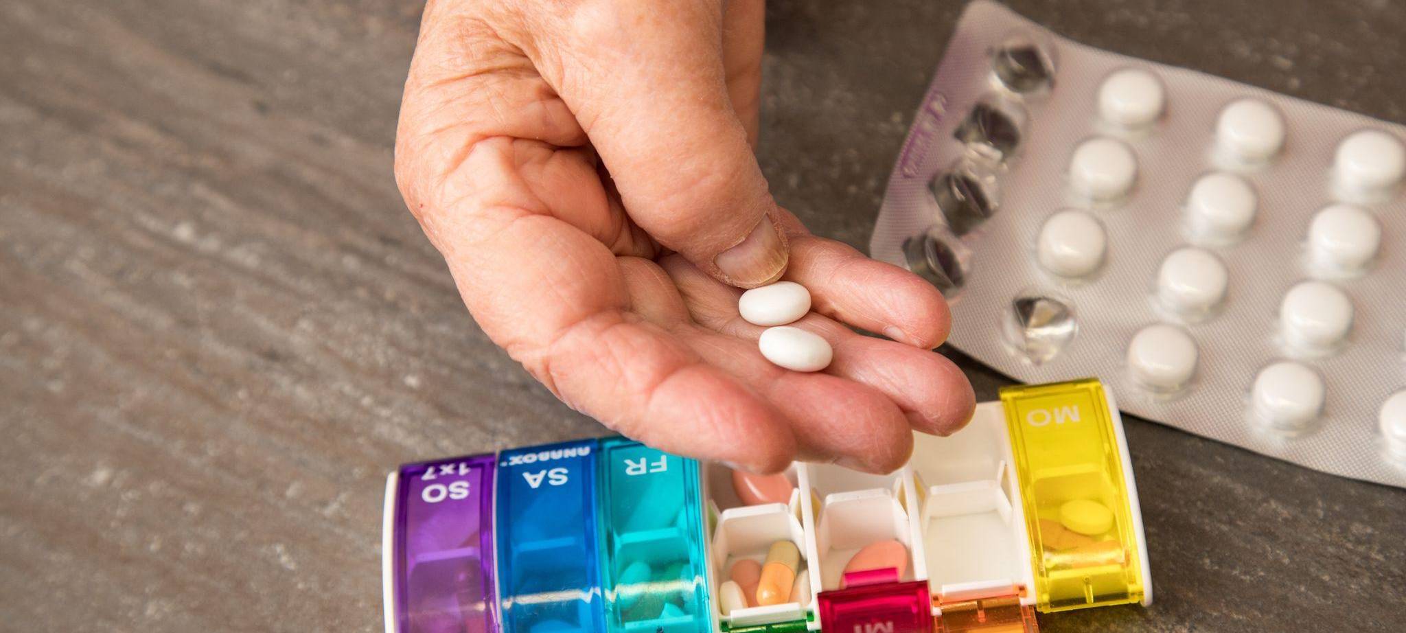 Seniorin nimmt Tabletten aus einer Pillendose