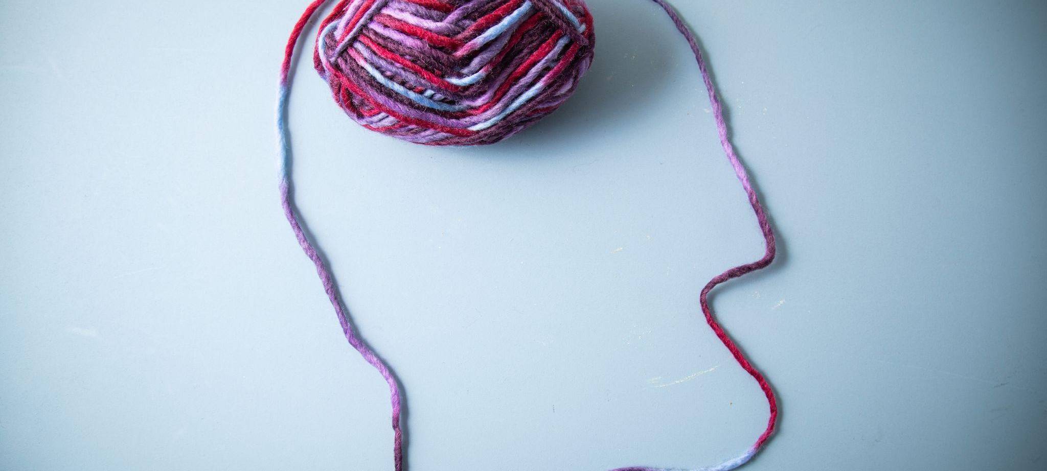 Die Silhouette eines Menschen und dessen Gehirn aus Garn