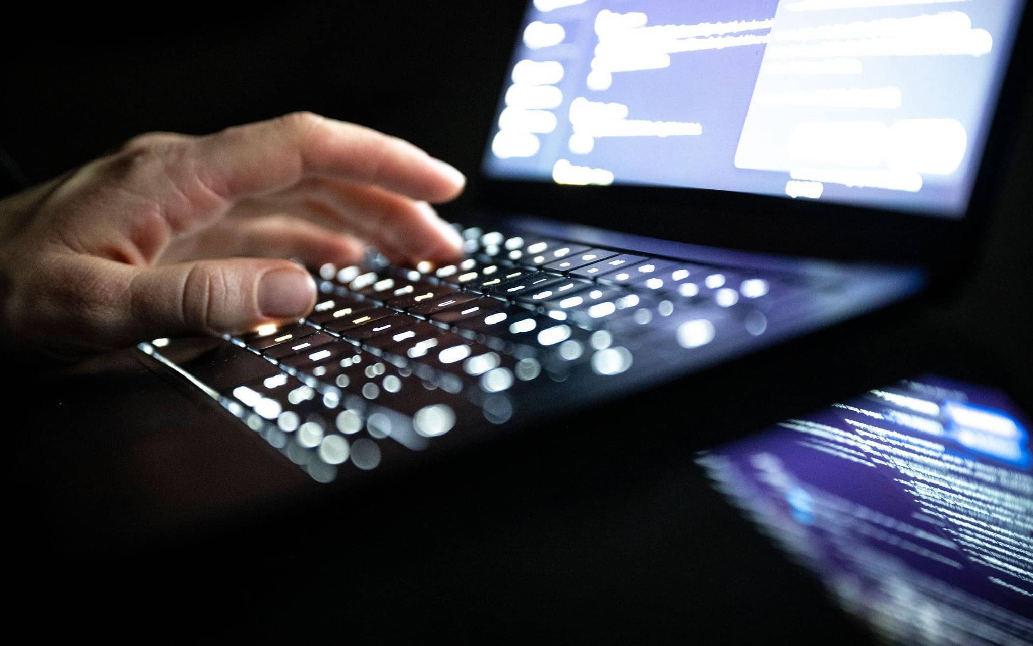 Eine Person tippt auf einer beleuchteten Laptop-Tastatur