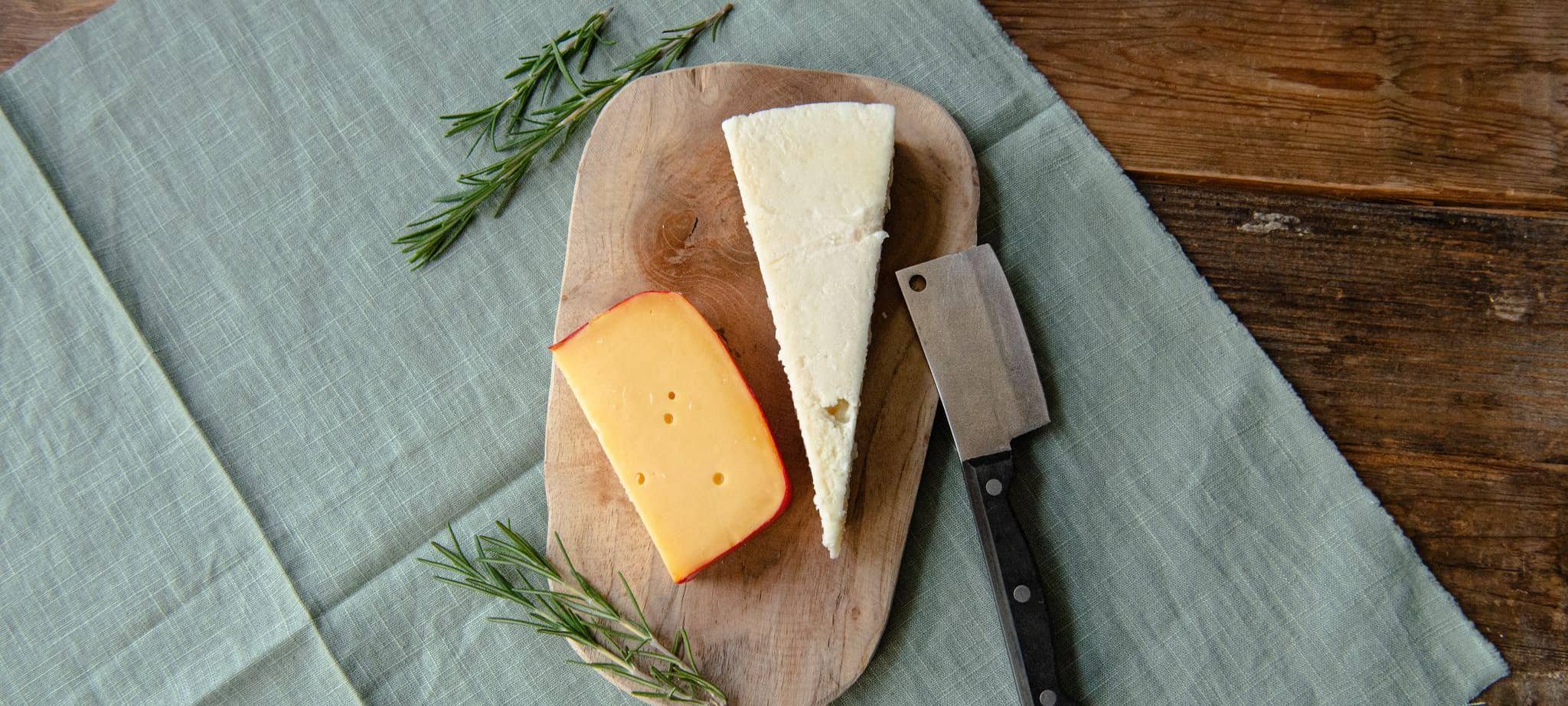 Gouda (l) und Parmesan liegen auf einem Holzbrett