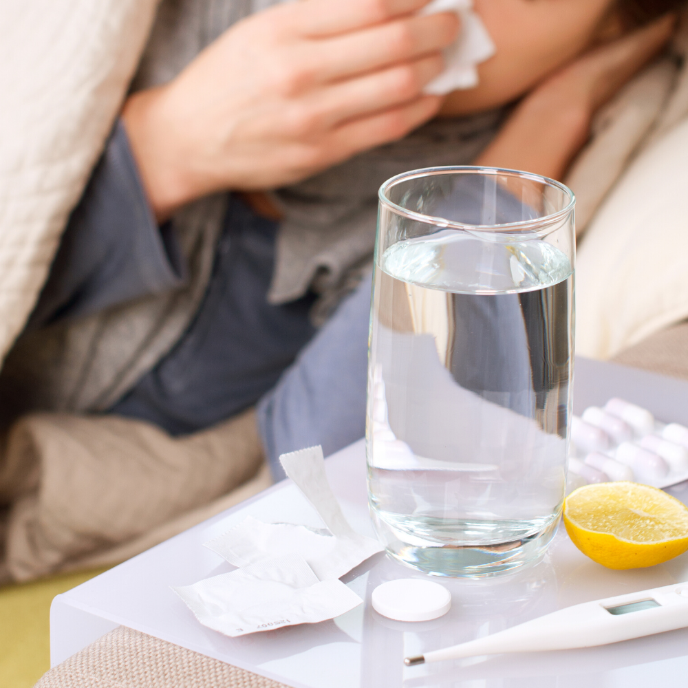 Auf dem Nachttisch einer erkälteten Person steht ein Tee und daneben liegt ein Fieberthermometer.